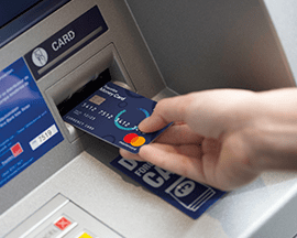 A hand inserts a card in an ATM