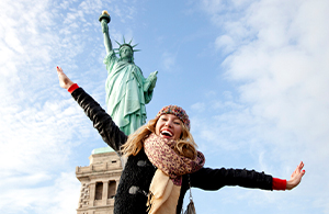 happy young person in front of the statue of liberty