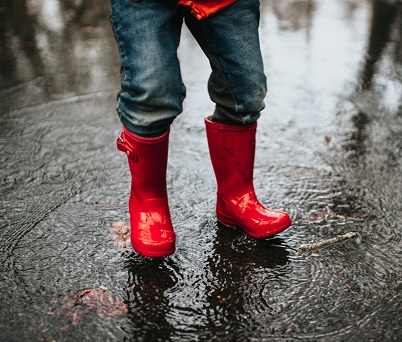 Red boots in rain puddle