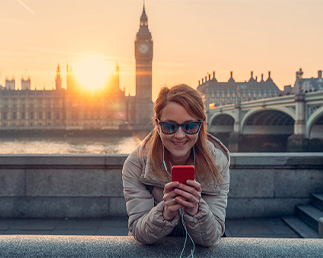 Woman smiling while texting in front of the river Thames and Big Ben in London