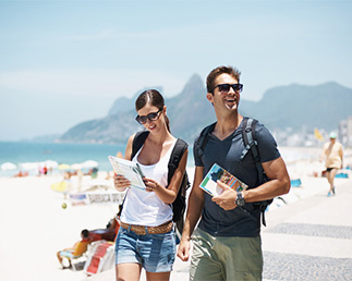 Couple holding maps while walking along side a beach